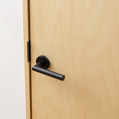 ナチュラルウッドの室内ドアに取り付けられた、マットな黒のレバーハンドルのイメージ写真