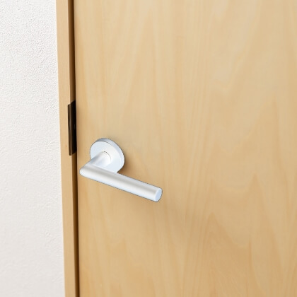ナチュラルウッドの室内ドアに取り付けられた、光沢のある白いレバーハンドルのイメージ写真